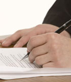 Imagen de las manos de una persona tomando anotaciones sobre unos documentos.