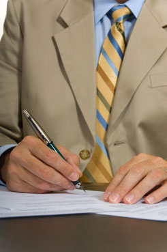 Imagen de las manos de un inversor realizando anotaciones sobre papeles con información económica.